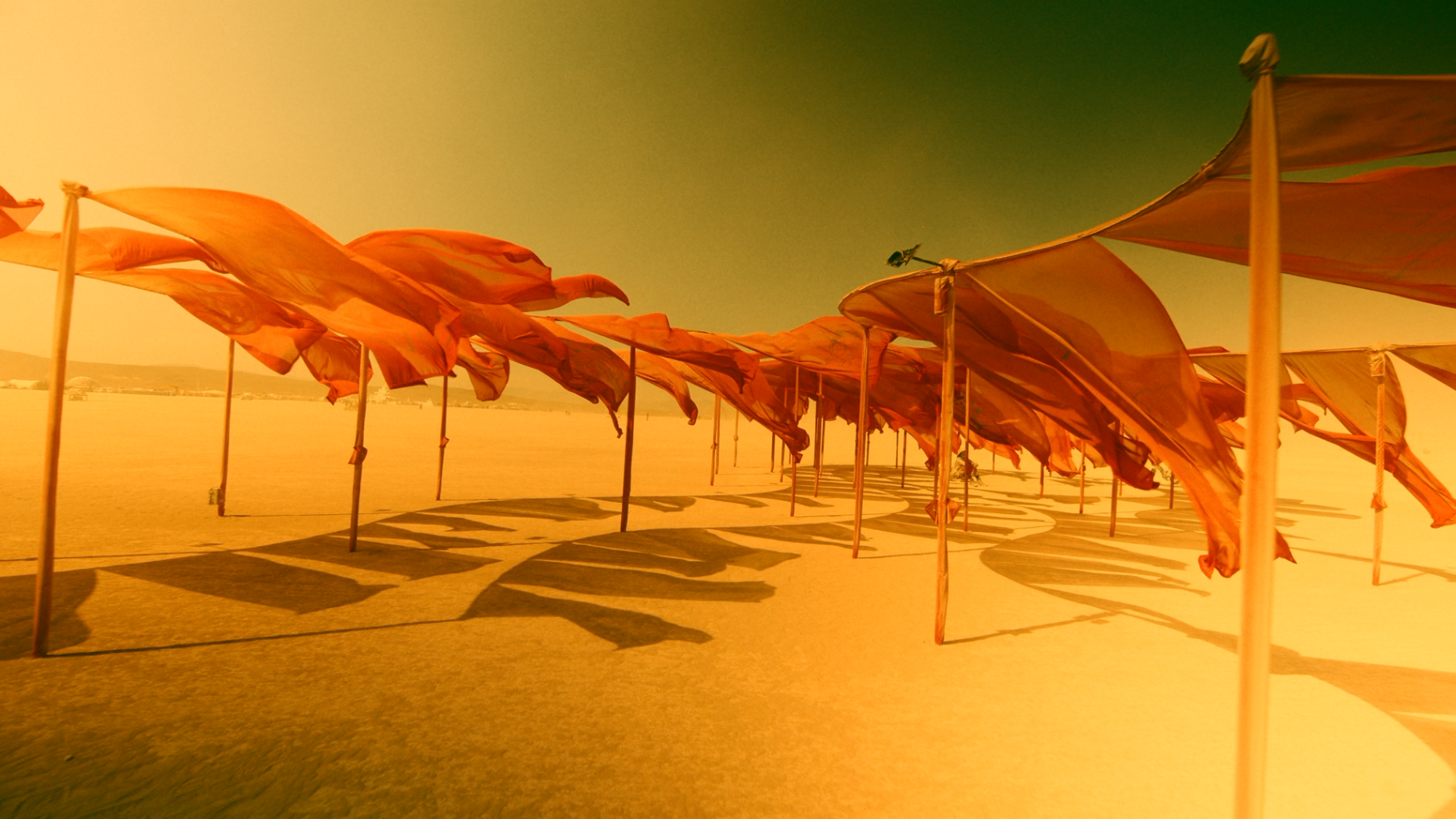 Cinematic desert scene with orange fabric structures in the wind